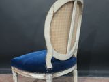 an old chair with a blue velvet seat and a white frame