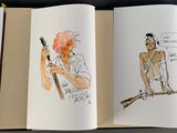 three open books with drawings on them on a table