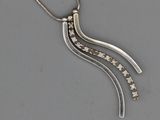 un gros plan d'un collier en argent serti de diamants sur un fond gris