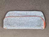 un gros plan sur une trousse de couleur grise et orange posée sur une table