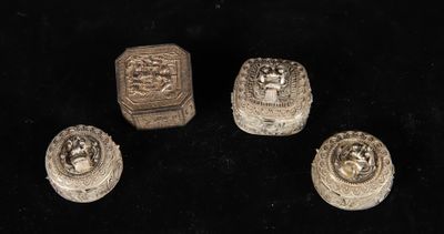 four small silver objects are sitting on a black surface