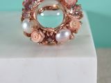 Bague en quartz rose et perle posée sur un bloc de marbre blanc