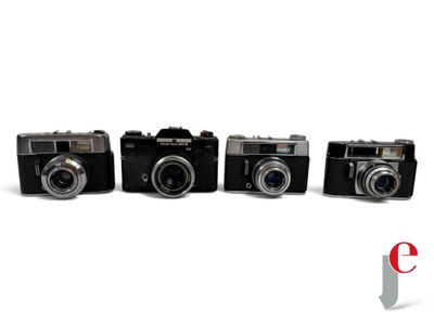 four cameras are lined up in a row on a white surface