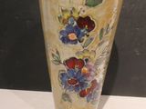 a vase with flowers painted on it sitting on a table