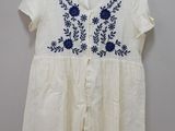 a white shirt with blue flowers on it hanging on a hanger