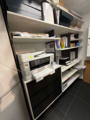 une imprimante posée sur une étagère dans un coin de la pièce