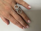 woman ' s hand holding a diamond ring on a white surface