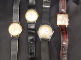 quatre montres sont alignées sur une surface noire