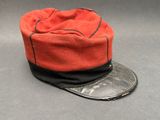 un chapeau orange orné d'un ruban noir et d'une pièce de monnaie, posé sur une surface grise