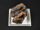 une assiette blanche sur laquelle repose un morceau de viande, posée sur une table noire