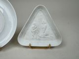 two white plates with a triangle shaped design on them next to a plate with a triangle shaped design on it
