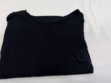 un t-shirt noir posé sur une surface blanche, avec un fond blanc