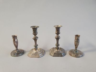 trois bougeoirs en argent sont posés sur une surface blanche
