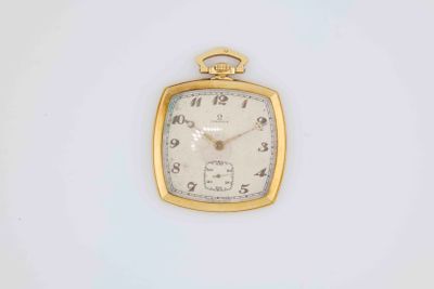a small gold pocket watch sitting on a white surface