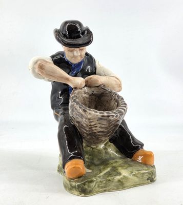 a figurine of a man sitting on a rock with a basket
