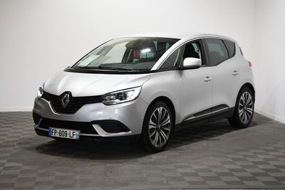 une voiture blanche est garée dans une pièce au sol à carreaux