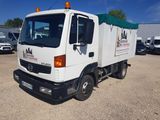 un camion blanc avec un auvent vert garé sur un parking