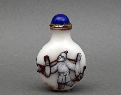 une image représentant une fiole à priser en verre blanc et bleu, sur laquelle figure un homme tenant une batte de baseball