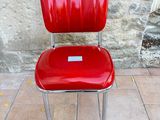 a red chair that is sitting in front of a stone wall