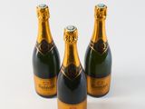 three bottles of champagne sitting next to each other on a white surface