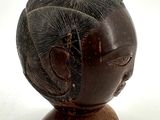 a small wooden head with a hair style on it
