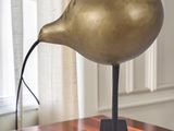 a gold bird statue on a wooden table in front of a window