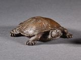 bronze figurine of a turtle and a ball on a gray surface