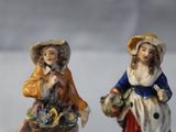 two figurines of women with baskets of flowers on them