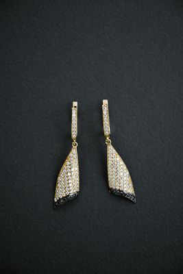 a pair of gold and diamond earrings on a black background