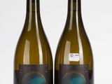 deux bouteilles de vin sont posées l'une à côté de l'autre sur une surface blanche