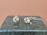une paire de boucles d'oreilles à clous en diamant jaune posée sur un bloc de marbre