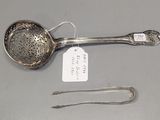 a silver spoon with a tag on it and a pair of tonges