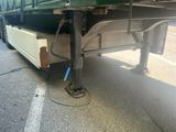 a green semi truck with a flat bed parked on the side of the road