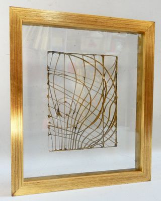 golden framed picture of a piece of art on a white surface