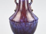 a purple and blue vase sitting on a white surface