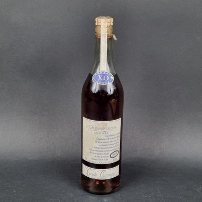 une vieille bouteille de vin posée sur une table, sur fond gris