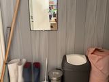 several pairs of rain boots are lined up next to a trash can and a mirror
