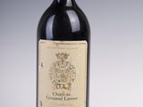 une vieille bouteille de vin rouge posée sur une table blanche