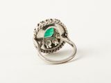 a close up of a ring with a green stone in it