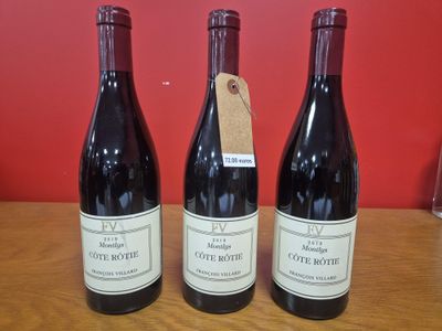 Trois bouteilles de vin sont posées sur une table, accompagnées d'une étiquette