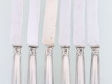 six silverware knives and a knife on a white surface