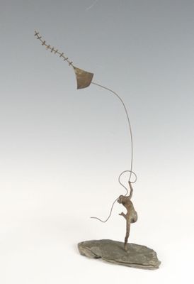 une sculpture représentant un homme faisant voler un cerf-volant sur un rocher