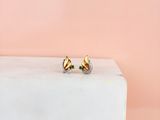 des boucles d'oreilles à clous plaquées or posées sur un bloc de marbre, sur fond rose