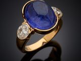 a close up view of a sapphire and diamond ring on a black surface