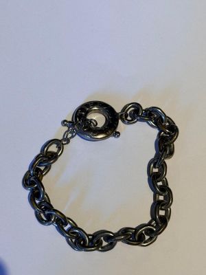 un gros plan d'un bracelet à maillons posé sur une surface blanche
