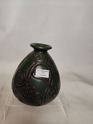 un vase vert muni d'une étiquette, posé sur une surface blanche