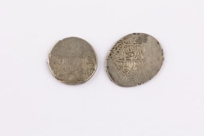 two silver coins sitting next to each other on a white surface