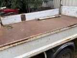 a rusted white truck with a flat bed in the back