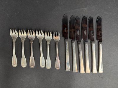 six fourchettes et six couteaux sont alignés sur une table