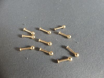 six pairs of gold plated screws on a gray surface